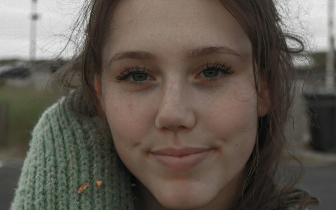 a woman with a green sweater and a cell phone