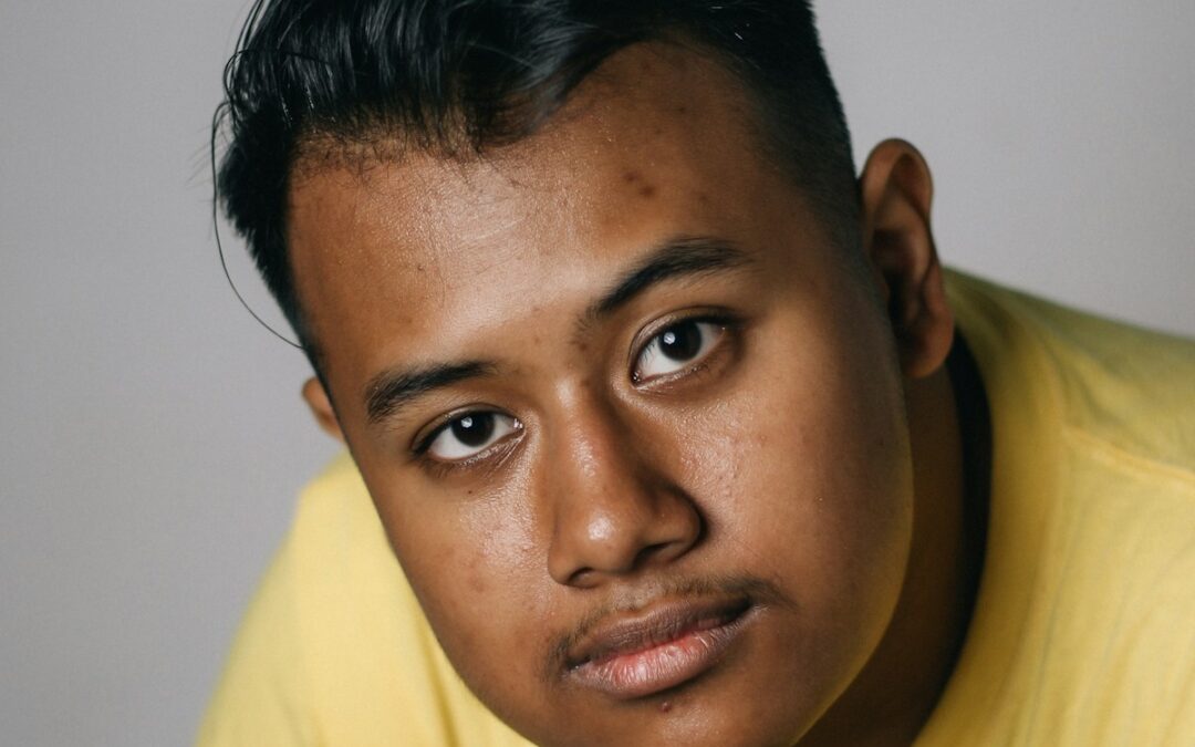 man wearing yellow crew-neck top near white wall