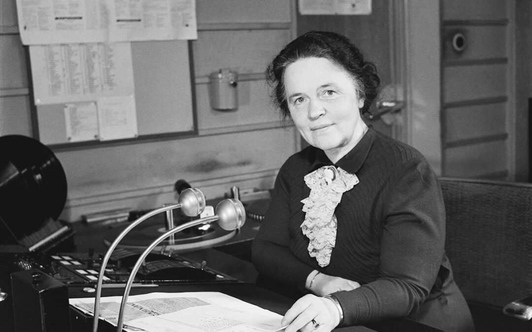 a woman sitting at a desk in front of a microphone